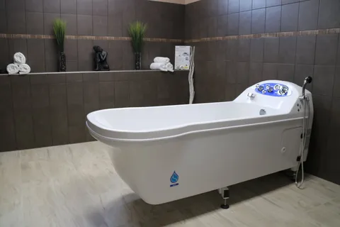 Bathing room with an accessible bathtub and tiled walls.