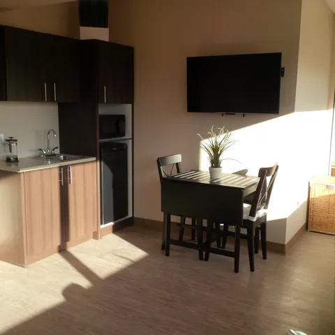 Suite kitchenette and dining table beneath a wall-mounted television.