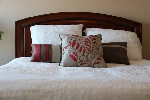 Bed with a wooden headboard, pillows and patterned cushions.