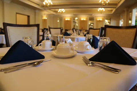 Dining room with upholstered chairs and tables set for a meal.