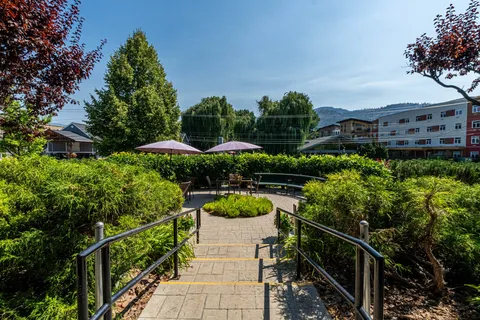 Garden steps with handrails leading to shaded outdoor tables and a bench