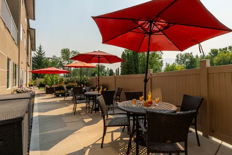 Patio with wicker chairs, round tables, red umbrellas and flower planters