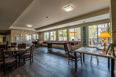 Room with a shuffleboard table, piano, tables and a partly completed jigsaw puzzle