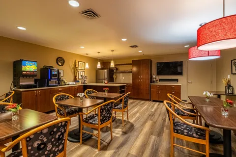 Room with tables, wooden chairs, beverage machines and a wall-mounted television