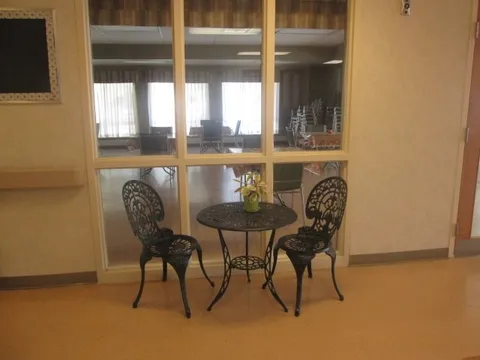 Two metal chairs and a small round table beside interior windows