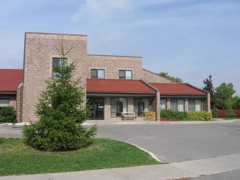 Brick residence with a red roof and a tree beside the driveway