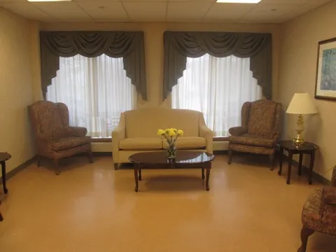 Sofa and two armchairs around a coffee table beneath curtained windows