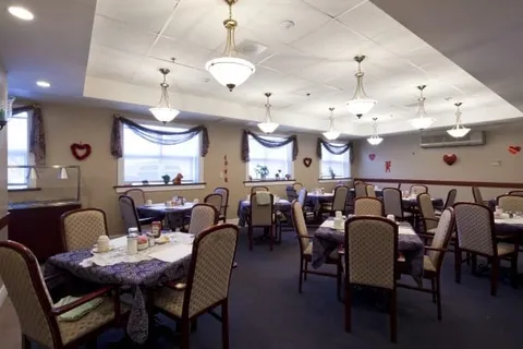 Dining room with upholstered chairs, covered tables, chandeliers and curtained windows