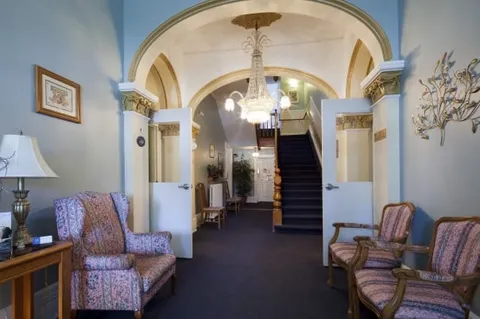 Room with patterned armchairs, arched doorways, chandeliers and a staircase