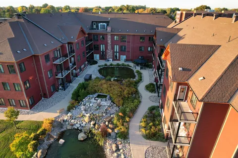 Aerial view of red brick buildings around a courtyard with ponds, stonework and paths