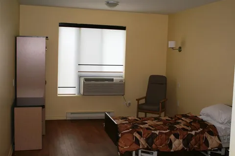 Bedroom with a single bed, armchair, cabinet and window