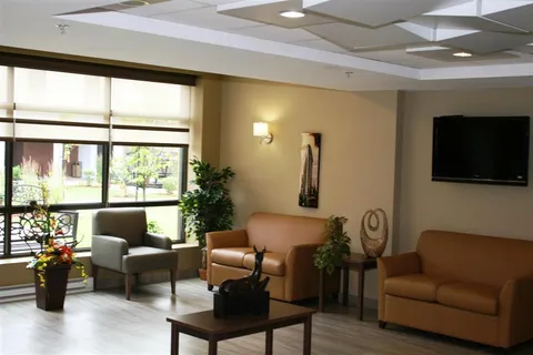 Sitting room with sofas, an armchair, plants and a wall-mounted television