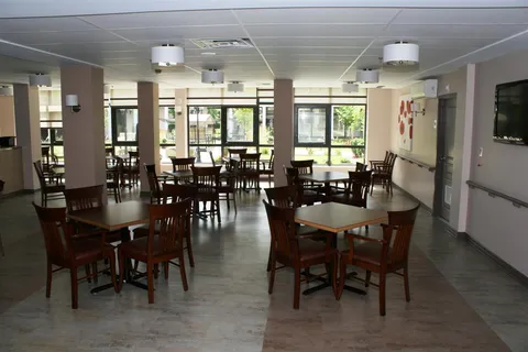 Dining room with wooden tables and chairs beside windows