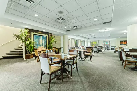 Room with tables, chairs, large windows and a short staircase