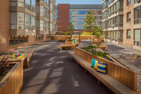 Residence buildings beside a courtyard with wooden benches and raised planters