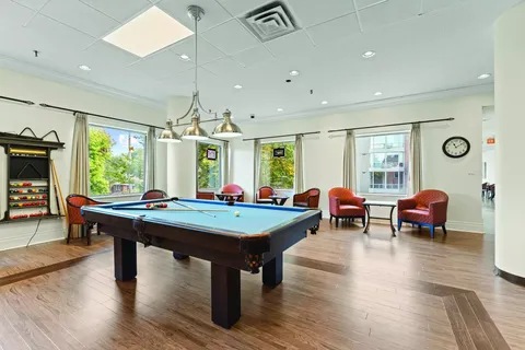 Pool table beside red chairs and large windows