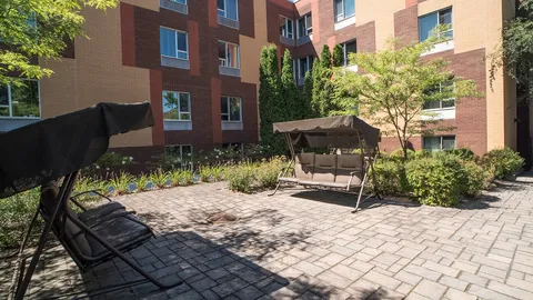 Paved courtyard with covered swings and planting beside the residence.