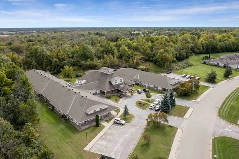 Aerial view of a low-rise building with driveways, lawns and surrounding trees