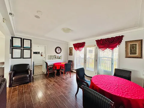 Dining area with round tables, black chairs and red tablecloths.