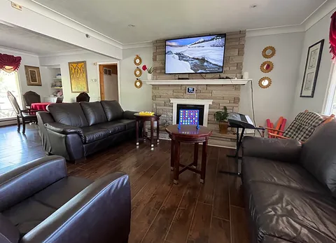 Lounge with leather sofas, a stone fireplace and a television.