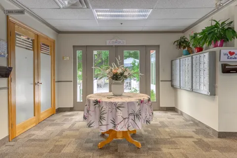 Entrance lobby with glass doors, mailboxes and a table with flowers
