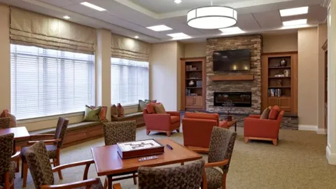 Lounge with armchairs, tables, a television and fireplace.
