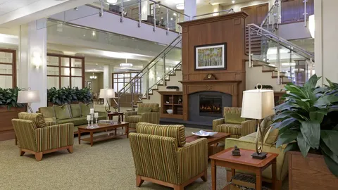 Atrium lounge with armchairs, fireplace and stairs to an upper balcony.