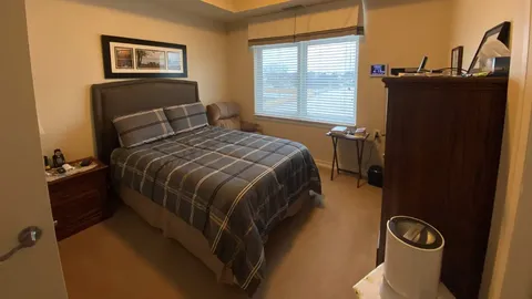 Bedroom with a bed, window and wooden dresser.
