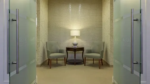 Small sitting area between doors with two armchairs and a lamp.