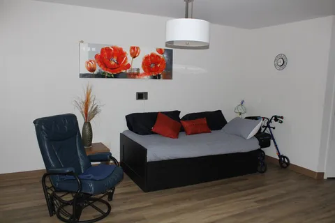 Bedroom with a single bed, armchair and framed flower picture