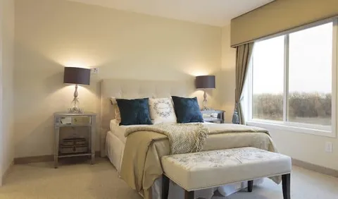 Bedroom with a bed, upholstered bench and large window