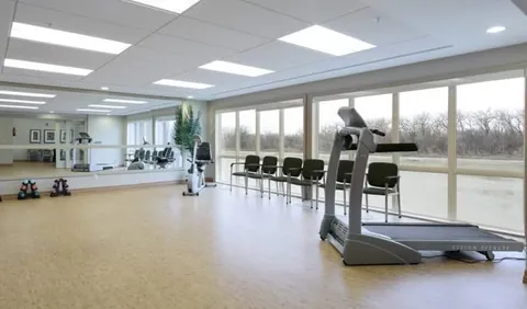 Exercise room with a treadmill, exercise bike, mirrored wall and large windows