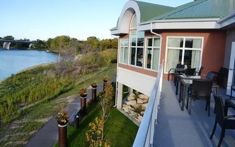 Building with a glass-enclosed room and balcony beside a river