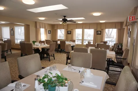 Dining room with upholstered chairs, set tables and large windows.
