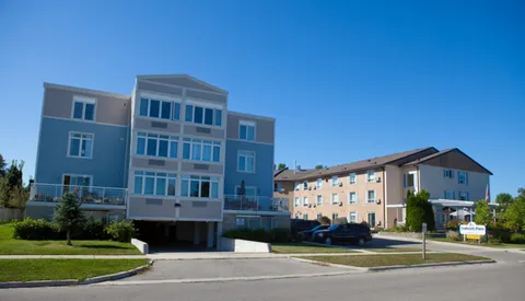 Residence exterior with a driveway, lawns and parked cars.