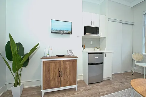 White kitchenette beside a small sideboard and seating.