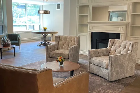 Armchairs around a coffee table beside a fireplace and window.