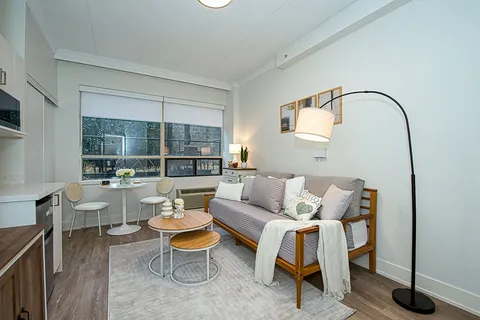 Suite sitting area with a sofa, tables and broad window.