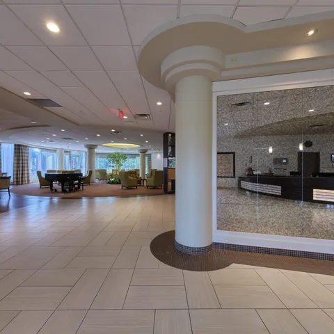 Reception desk in a tiled lobby with columns and a grand piano