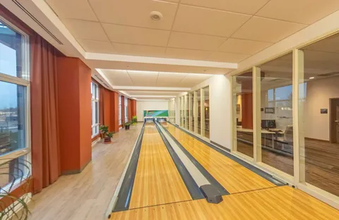 Indoor bowling lane beside windows and an adjoining exercise room