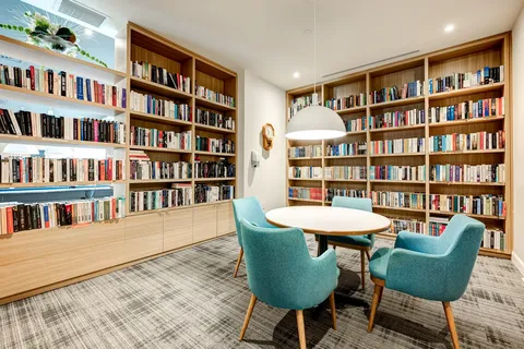 Library with bookshelves, blue armchairs and a round table