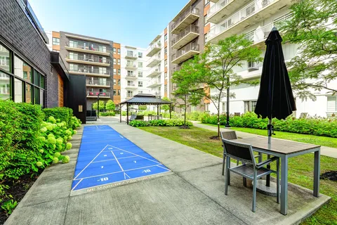 Residence wings around a planted courtyard with a shuffleboard court and patio table