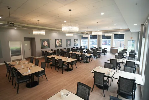 Dining room with square tables, dark chairs and chandeliers