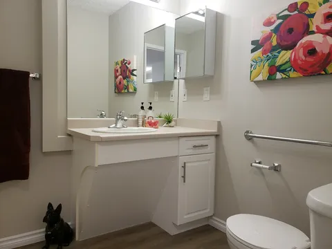 Bathroom with a sink, toilet, mirror and floral wall art
