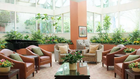 Bright atrium lounge with armchairs and indoor planting.