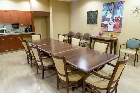 Dining area with wooden tables, upholstered chairs and a kitchenette