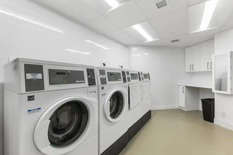 Laundry room with white washers, dryers and wall cabinets