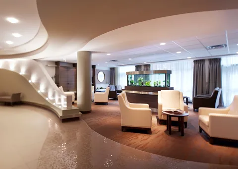 Armchairs around an aquarium beside a curved staircase and large windows