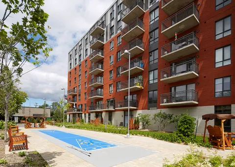 Brick building with balconies overlooking a shuffleboard court and wooden patio swings