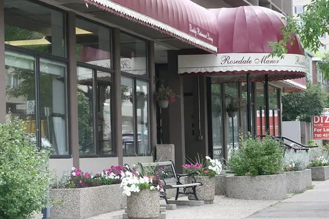 Residence entrance beneath a curved awning with flower planters.